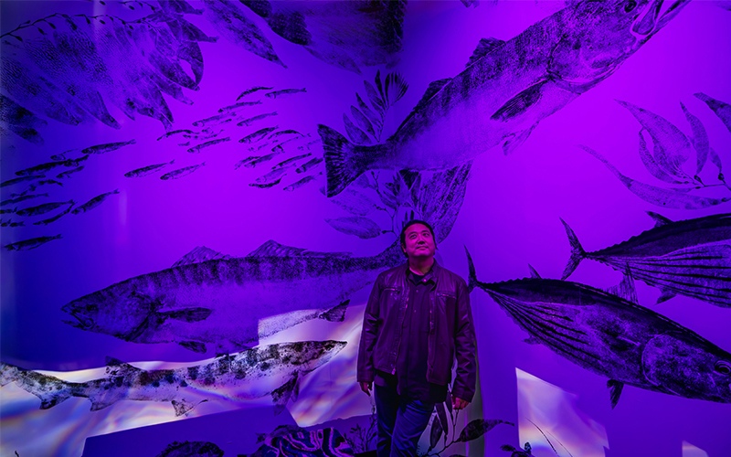 Dwight Hwang stands in front of his fish print mural