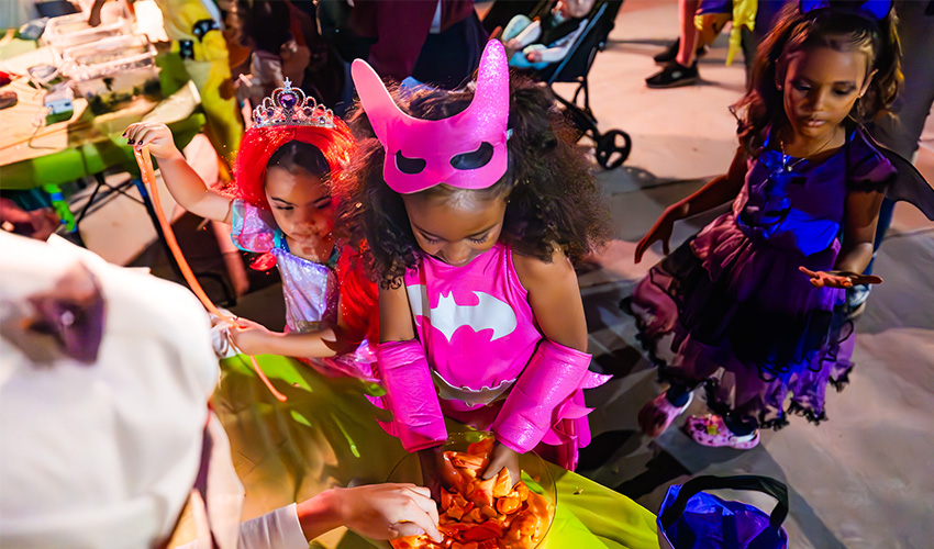 Children adorned in Halloween attire delight in playing with slime amidst the festivities of Halloween Aglow.