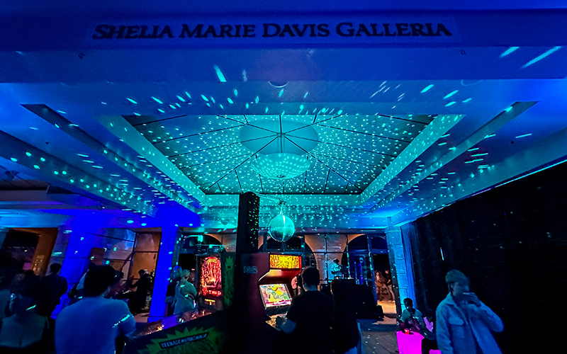 Guests enjoying arcade games beneath a sparkling disco ball, with vibrant lights illuminating the space.