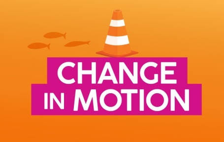 Graphic featuring the phrase 'Change in Motion' prominently displayed. A bright orange construction cone is positioned in the foreground.