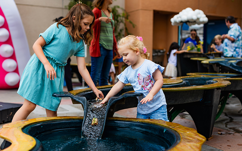 Children happily playing with Riveropolis, an interactive water-play experience featuring a miniature river.