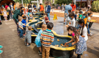 guests interact with a Riveropolis installation, building small model boats that float down a winding model river