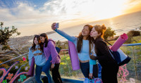 Students pose for photos in front of a glowing sunset view at Birch Aquarium