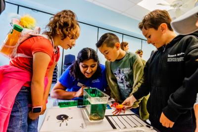 A Birch Aquarium educator and students observe a small crab.