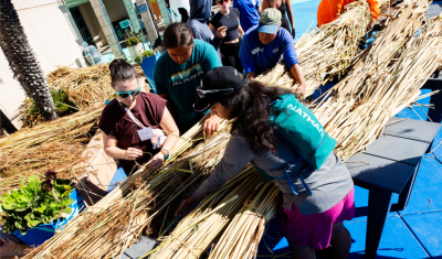 Birch Aquarium guests participate in a tule boat build during Indigenous Ocean Day 2024