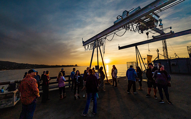 Tour participants watch a sunset from Scripps Pier.