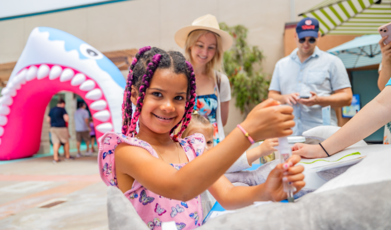 guests stand at a shark exploration station, with a large inflatable shark mouth in the background